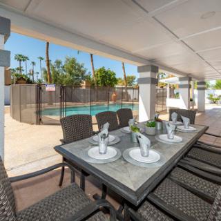 A stylish outdoor dining area overlooking a refreshing pool, perfect for sunny days.