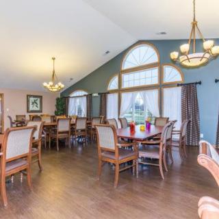 A spacious dining room with multiple tables and chairs, large windows, and elegant chandeliers.