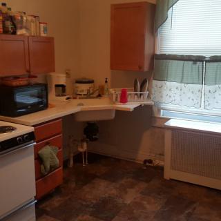 A cozy kitchen with wooden cabinets, a stove, and a microwave on the countertop.