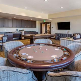 A spacious and modern game room featuring a poker table, comfortable seating, and a large television.