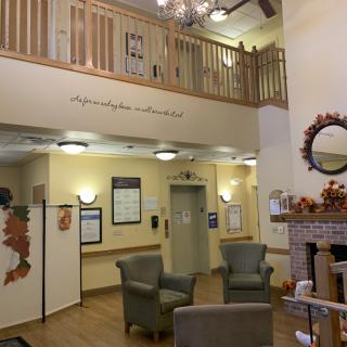 A cozy lobby area with autumn-themed decorations, featuring a seating area, fireplace, and chandelier.