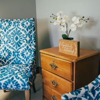 A cozy corner featuring patterned chairs and a wooden nightstand, adorned with an elegant orchid.
