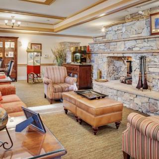 A cozy living room with a stone fireplace, comfortable seating, and warm decor.