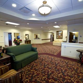 A spacious lobby with a green sofa, decorative carpet, and a reception desk.