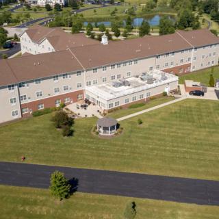 Aerial view of a large building with a well-maintained lawn and gazebo.