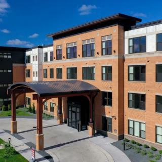 A modern brick building with a prominent arched entrance under a clear blue sky.