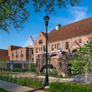 A picturesque view of a historical building with lush greenery and a flag waving in the breeze.
