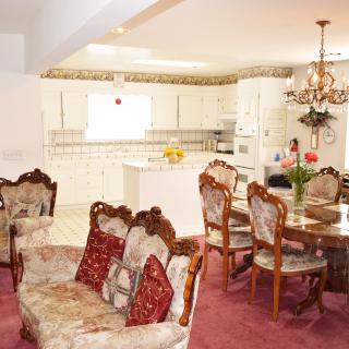 A vintage-style open-plan kitchen and living area with floral upholstered furniture and a chandelier.