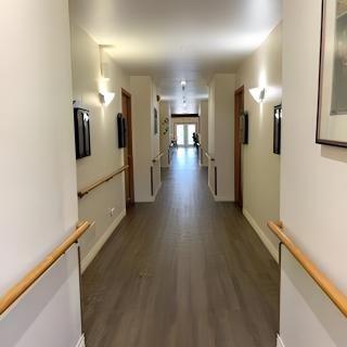A modern hallway with wooden floors and handrails, featuring several doors and soft lighting.