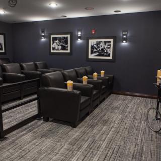 A cozy home theater with comfortable seating and framed photographs on dark walls.