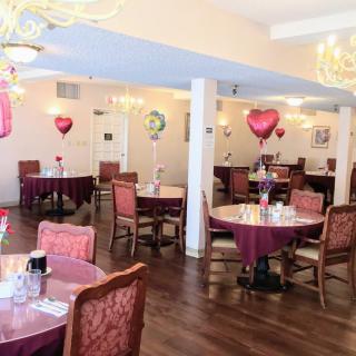A decorated dining area with tables, chairs, and heart-shaped balloons.