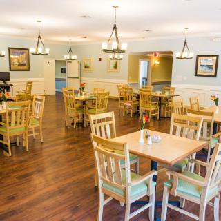 A spacious dining area with wooden tables and chairs, complemented by elegant chandeliers.
