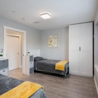 A modern bedroom with twin beds, featuring minimalist decor and a wardrobe.