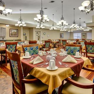 A well-decorated dining room with neatly arranged tables and chairs, featuring elegant chandeliers.