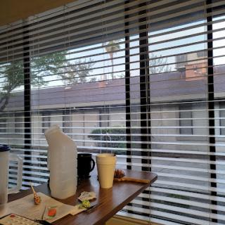 A view from inside a room showing blinds, a table with food and drinks, and an exterior scene.