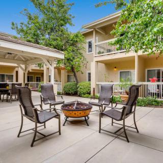 A cozy outdoor patio area with chairs arranged around a fire pit in an apartment complex courtyard.