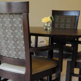 A modern dining area featuring a dark wooden table with matching chairs and a small floral centerpiece.