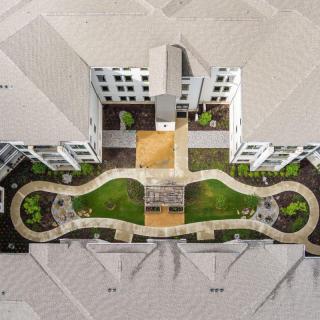 Aerial view of a building complex with a landscaped garden and winding pathways.