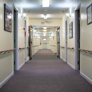 A long, well-lit hallway with doors on either side and handrails along the walls.
