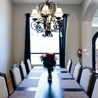 A well-decorated dining room with an elegant chandelier and a long table set for gatherings.