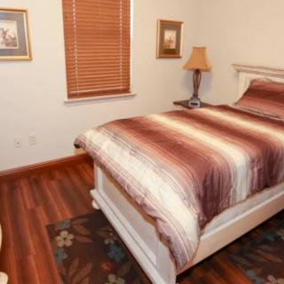 A cozy bedroom with a neatly made bed, wooden floors, and warm-toned decor.