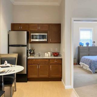 A compact kitchenette with a table in an apartment, adjoining a bedroom.