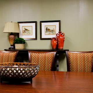 A stylish dining room featuring elegant furniture, decorative vases, and framed artwork on the walls.