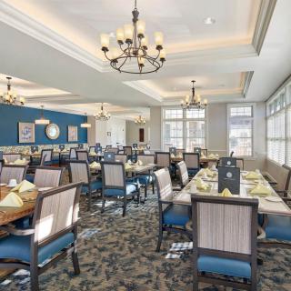 Elegant dining room with chandeliers and neatly arranged tables under natural light.