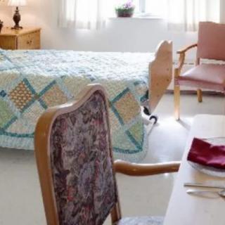 A cozy bedroom with a quilt-covered bed, chairs, and a table set for dining.
