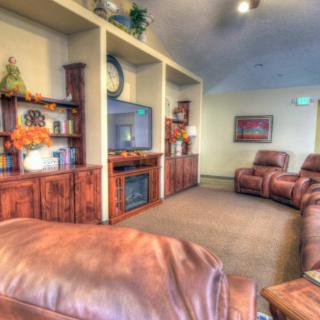 A cozy living room with leather couches, a television, and built-in bookshelves.