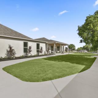 A suburban house with a well-maintained lawn and driveway under a clear blue sky.