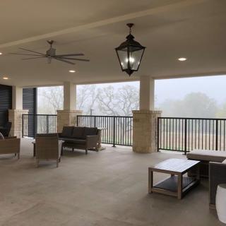 A spacious outdoor patio with comfortable seating and ceiling fans, offering a view of the surrounding landscape.