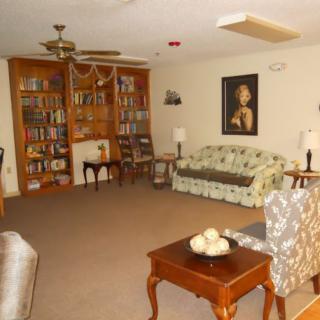 A cozy living room featuring a large bookshelf, patterned sofa, and classic furniture.