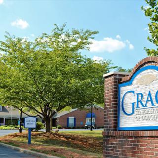A view of a brick sign and nearby buildings surrounded by trees under a clear sky.