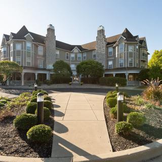 A grand hotel with classic architecture, surrounded by well-maintained gardens and a paved pathway.