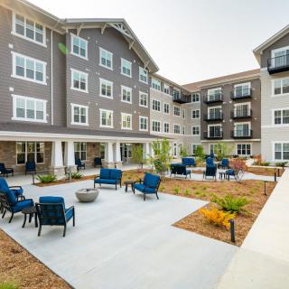 A modern apartment building featuring a spacious courtyard with outdoor seating and landscaped areas.