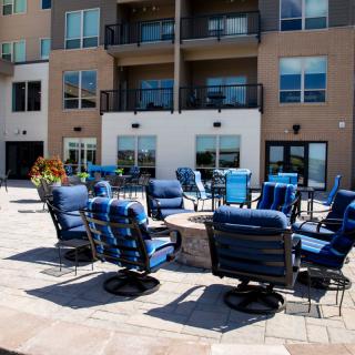 Outdoor seating area with blue-cushioned chairs at a modern apartment complex.