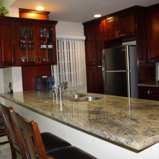 A modern kitchen featuring granite countertops and dark wooden cabinetry.