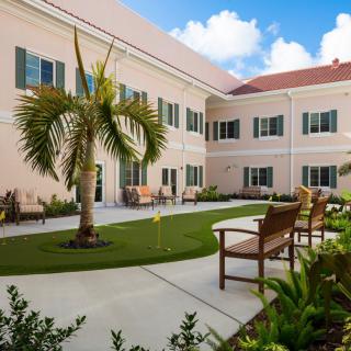 A well-maintained courtyard with a palm tree and benches in front of a building.