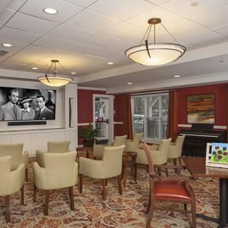 A cozy conference room with comfortable seating and a television displaying a black-and-white movie.