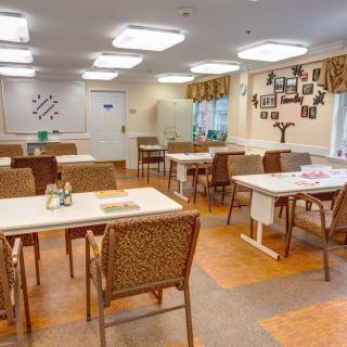 A clean and well-lit dining room with neatly arranged tables and chairs.