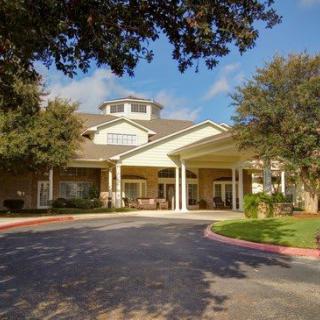 A large residential building with a covered entrance and surrounding trees.