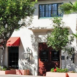 A charming building with a red awning, surrounded by trees and plants.