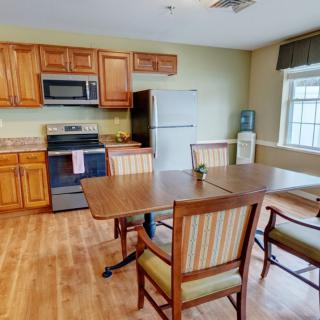 A cozy kitchen and dining area featuring wooden cabinets, a table with chairs, and standard kitchen appliances.
