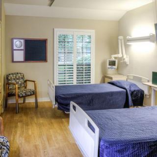 A clean and well-organized hospital room with two beds, medical equipment, and a window.