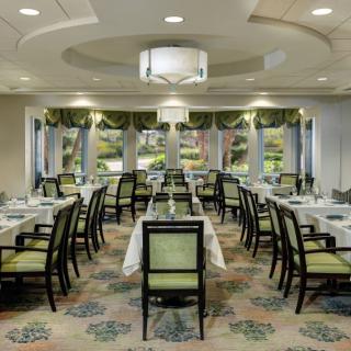 A beautifully arranged restaurant dining room with elegantly set tables and large windows.