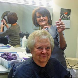 A cheerful client enjoying her salon experience while the hairdresser works on her hair.