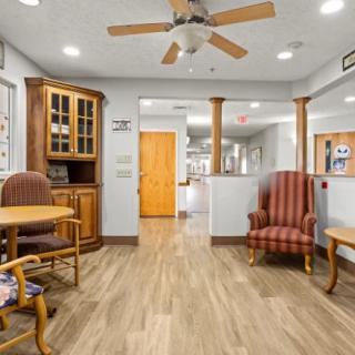 A cozy living area with wooden flooring, featuring comfortable seating and a ceiling fan.