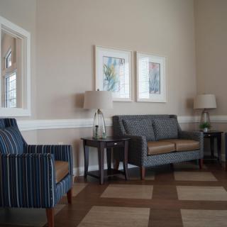 A cozy living room with a sofa, armchairs, lamps, and wall art.