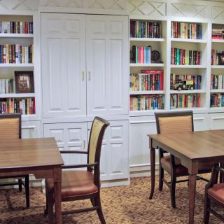 A cozy library room with bookshelves, tables, and chairs for reading.